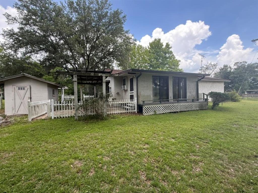 A single-story house with a wooden pergola, white picket fence, and a small detached shed — 5890 SE 145TH STREET, SUMMERFIELD, FL