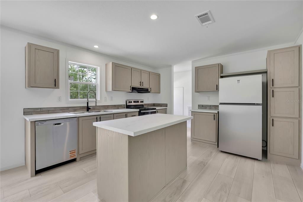 A kitchen features light wood cabinets, stainless steel appliances, a center island, and white countertops — 5611 W ROCHELLE STREET, HOMOSASSA, FL