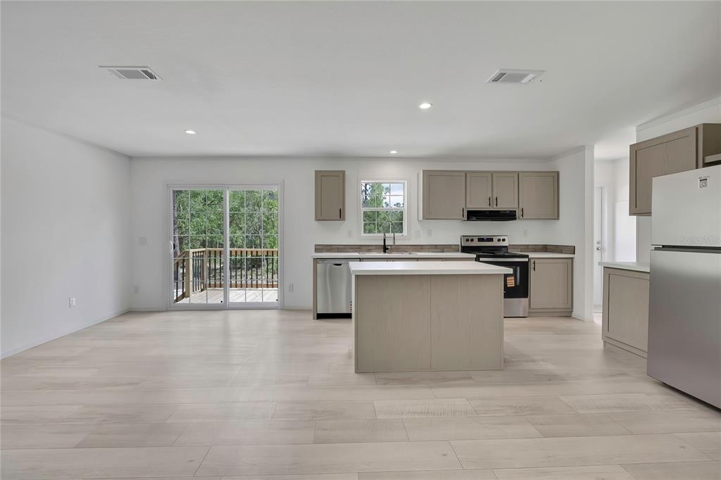 A kitchen with light wood cabinets, a central island, and sliding glass doors to a deck — 5611 W ROCHELLE STREET, HOMOSASSA, FL