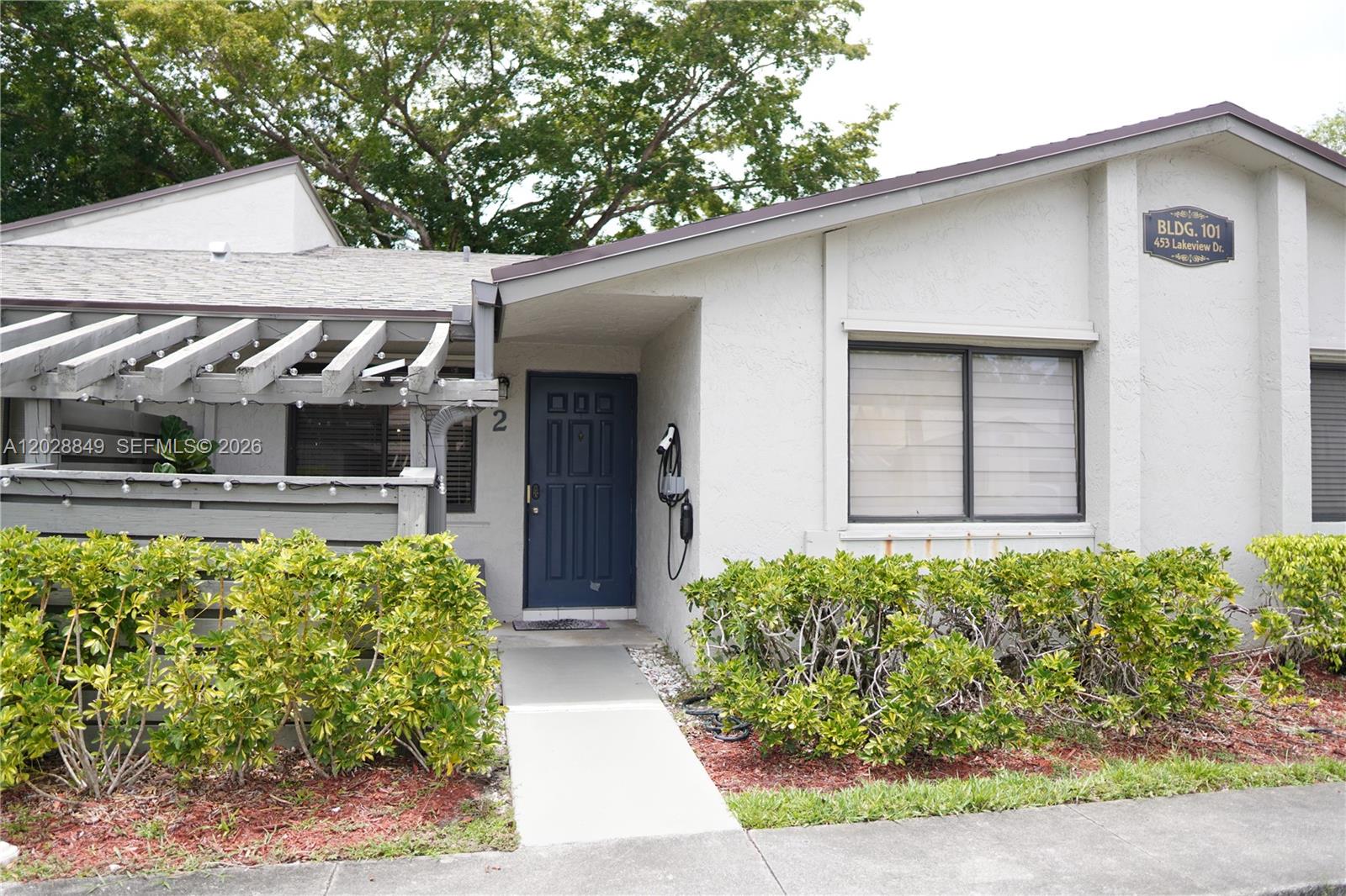 A single-story building exterior features a dark blue front door and a small patio area — 453 Lakeview Dr # 2, Weston FL 33326, WESTON, FL