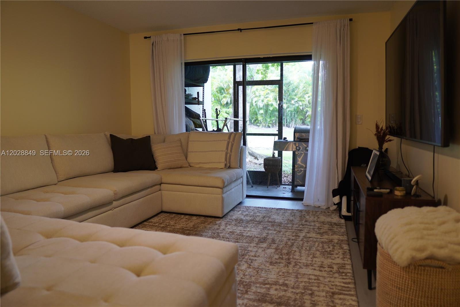 A living room features a sectional sofa, a television, and a sliding door to a patio — 453 Lakeview Dr # 2, Weston FL 33326, WESTON, FL
