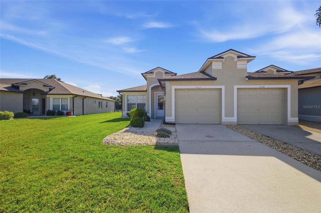 A duplex home with two beige garage doors and a shared concrete driveway — 13307 ASHBARK COURT, RIVERVIEW, FL