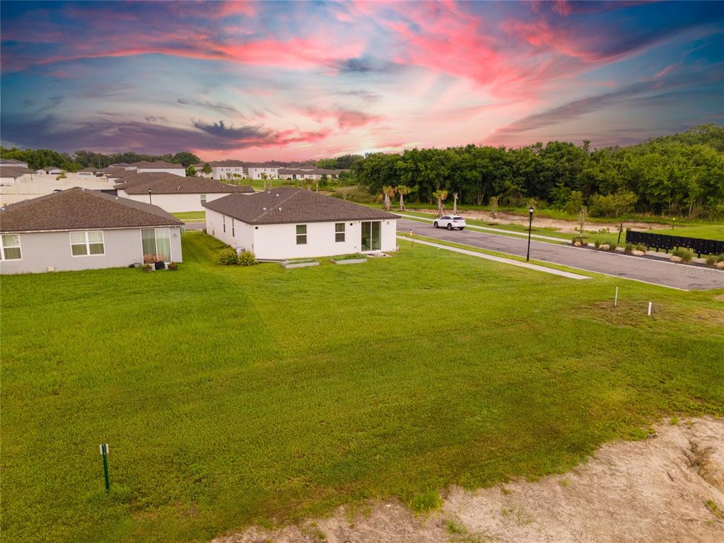 An aerial view shows the backyard of a suburban house with a large grassy lawn — 3303 ASHER MOON LANE, ZEPHYRHILLS, FL