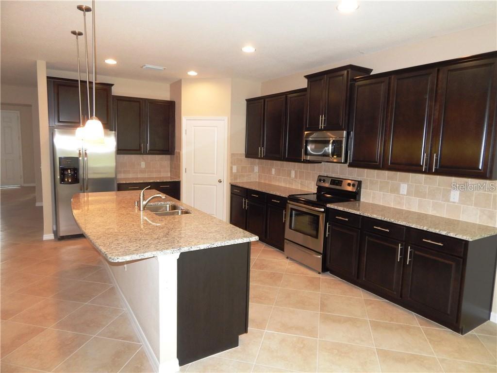 A kitchen features dark wood cabinets, granite countertops, stainless steel appliances, and a central island — 15302 LAS OLAS PLACE, BRADENTON, FL