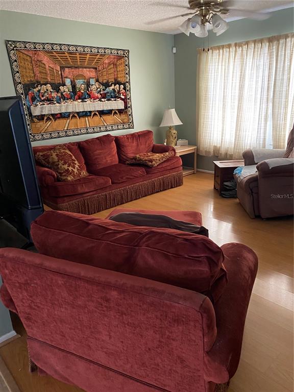 A living room features red upholstered furniture, a wall tapestry, and light wood flooring — 8503 GAILLARD AVENUE, NORTH PORT, FL
