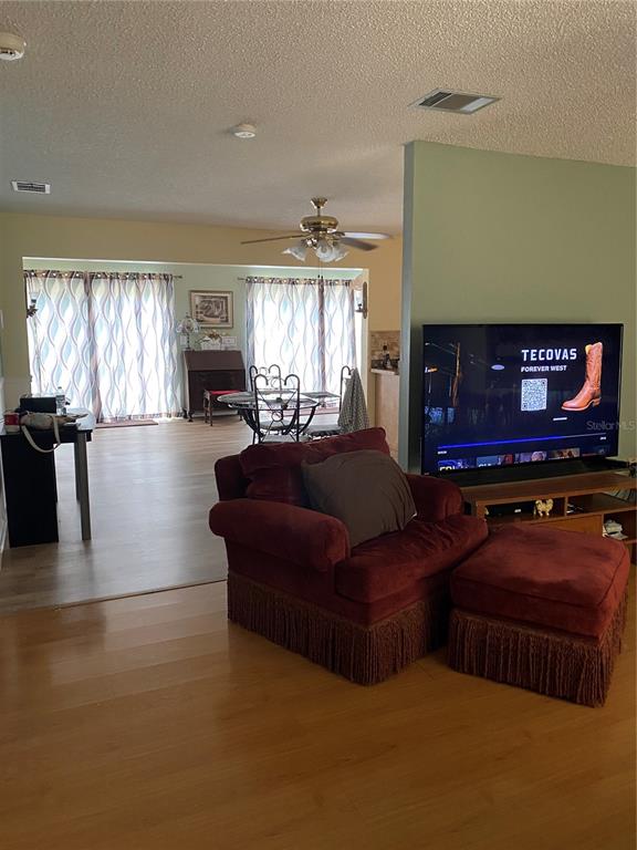 A living room features a red armchair with an ottoman and a television on a stand — 8503 GAILLARD AVENUE, NORTH PORT, FL