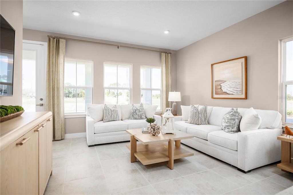 A living room features two white sofas, a wooden coffee table, and large windows — 640 STONELEIGH LANE, DEBARY, FL