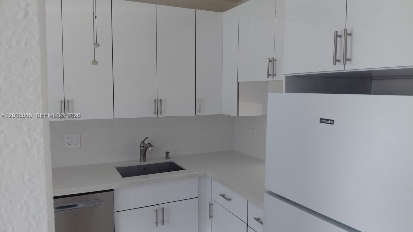 A kitchen features white cabinets, light countertops, a stainless steel sink, and a white refrigerator — 7897 Golf Cir Dr # 306, Margate FL 33063, MARGATE, FL