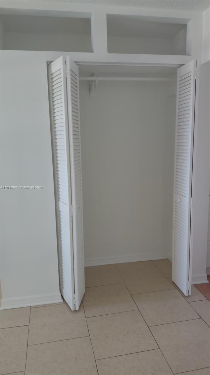 A white closet with louvered doors and overhead storage sits above a tiled floor — 7897 Golf Cir Dr # 306, Margate FL 33063, MARGATE, FL
