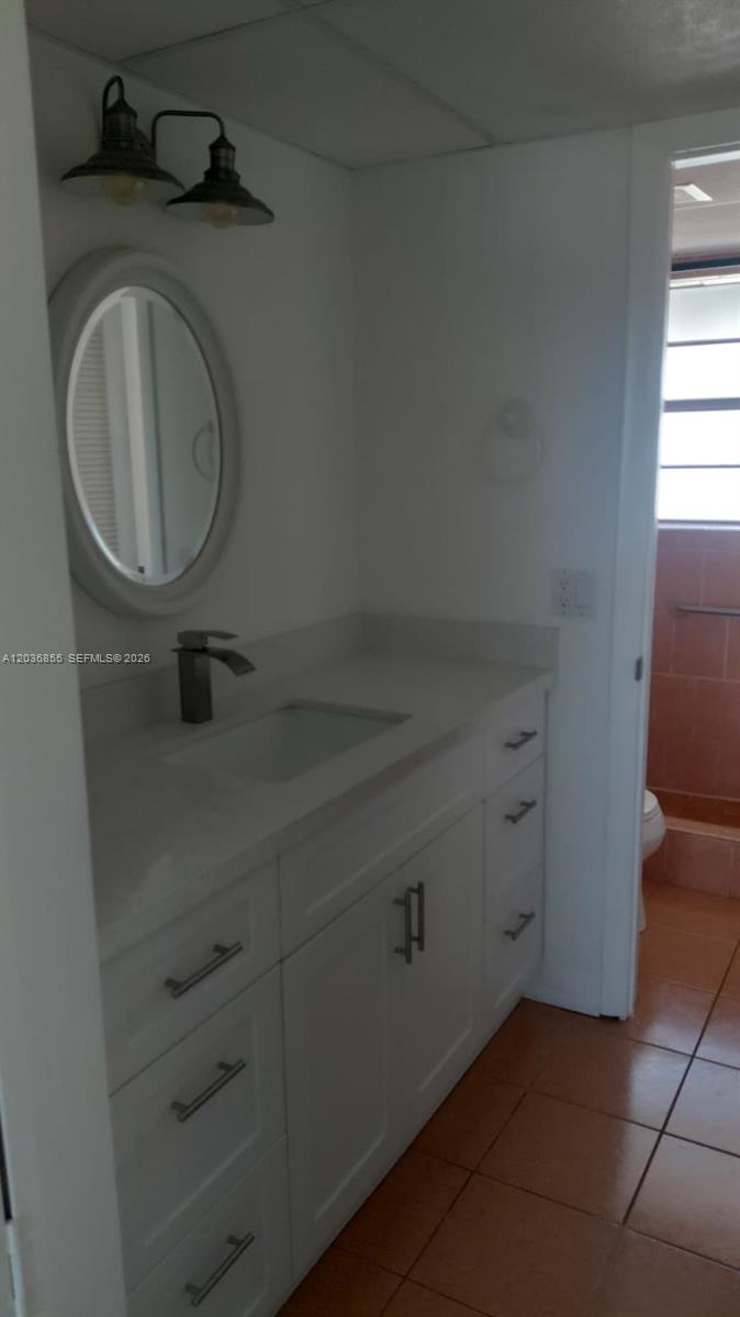 A bathroom features a white vanity with a sink, an oval mirror, and light fixtures — 7897 Golf Cir Dr # 306, Margate FL 33063, MARGATE, FL