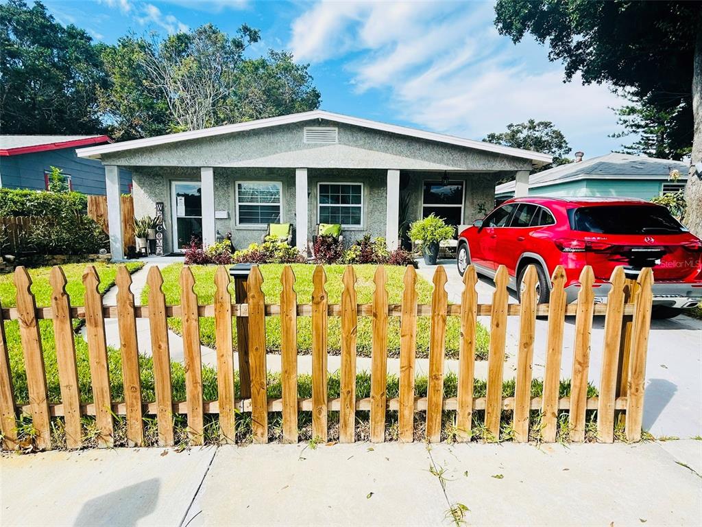 A single-story house with a wooden picket fence and a red car parked in front — 4611 14TH AVENUE S, ST PETERSBURG, FL