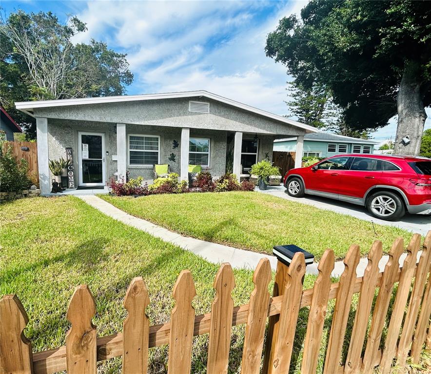 A single-story house with a covered porch, a front lawn, and a red car parked outside — 4611 14TH AVENUE S, ST PETERSBURG, FL