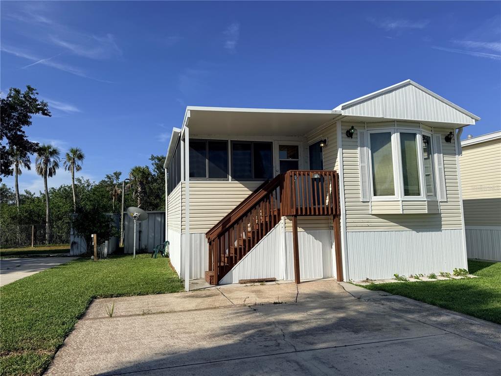 A light-colored mobile home features a screened porch, wooden stairs, and a concrete driveway — 2215 73RD STREET E UNIT 275, PALMETTO, FL