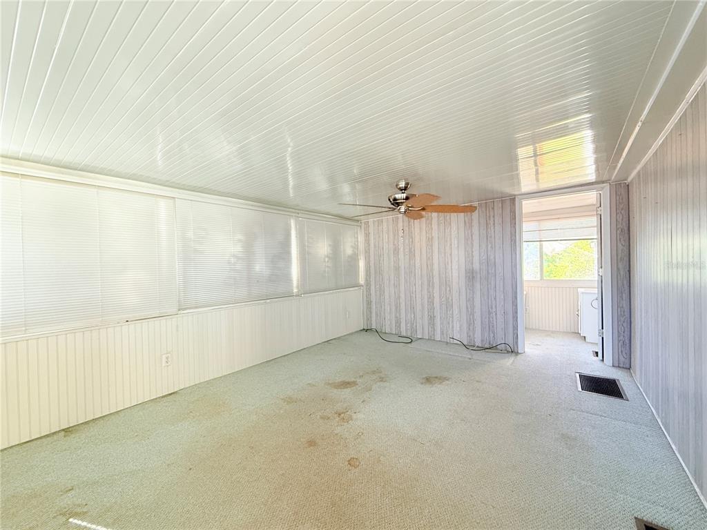 A sunroom with wood-paneled walls, a ceiling fan, and carpeted flooring — 2215 73RD STREET E UNIT 275, PALMETTO, FL