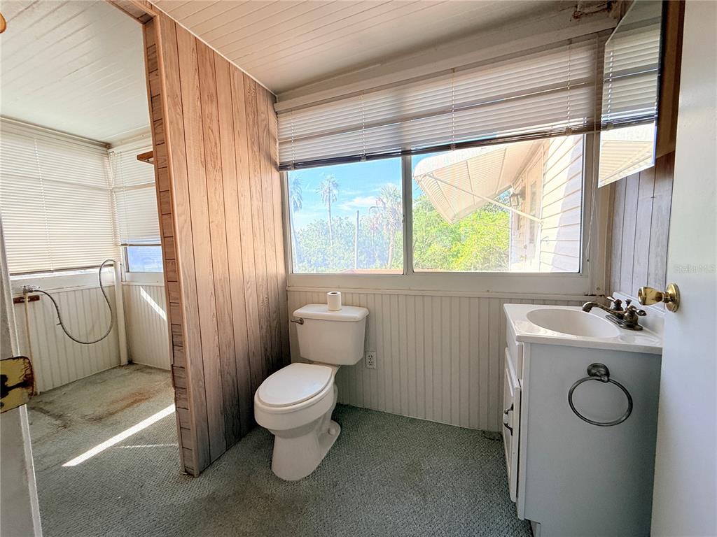 A bathroom features a toilet, a vanity sink, wood paneling, and carpeted flooring — 2215 73RD STREET E UNIT 275, PALMETTO, FL