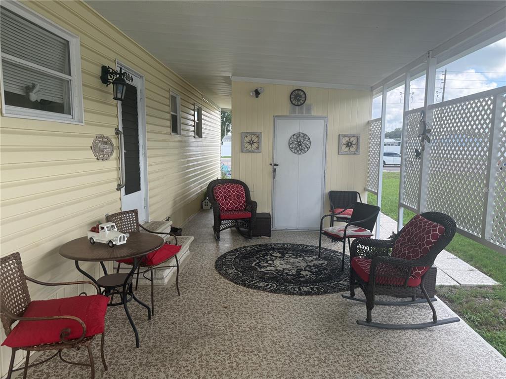A covered porch features light yellow siding, a patterned floor, and several wicker chairs — 37529 ATTICA AVENUE, ZEPHYRHILLS, FL