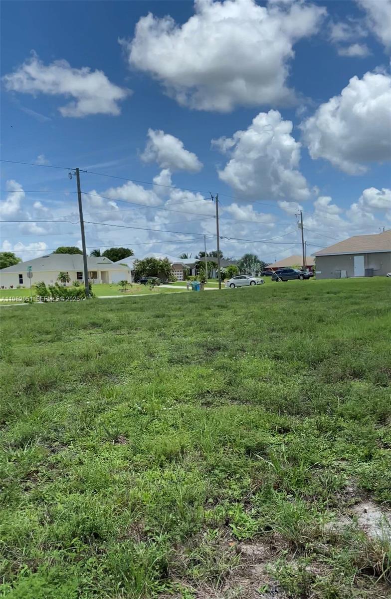 A vacant, grassy residential lot under a blue sky with scattered clouds — 2 NW 13TH PL, Cape Coral FL 33993, CAPE CORAL, FL