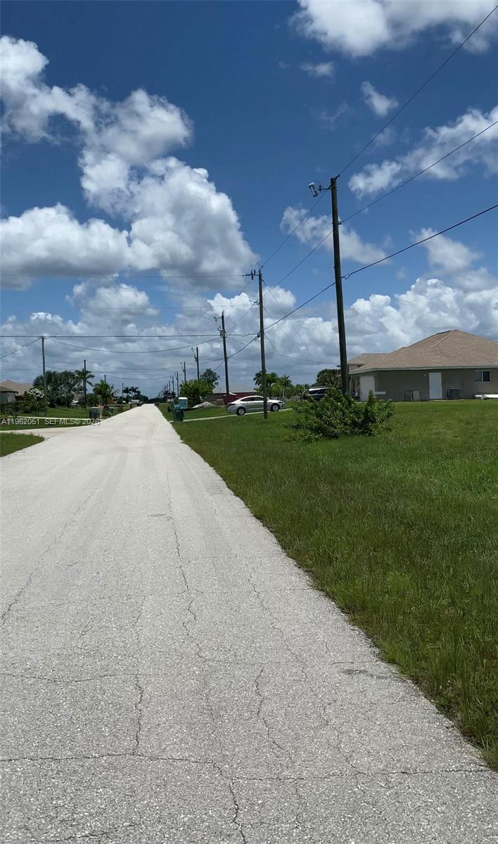 A paved road stretches into the distance past utility poles and a residential house — 2 NW 13TH PL, Cape Coral FL 33993, CAPE CORAL, FL