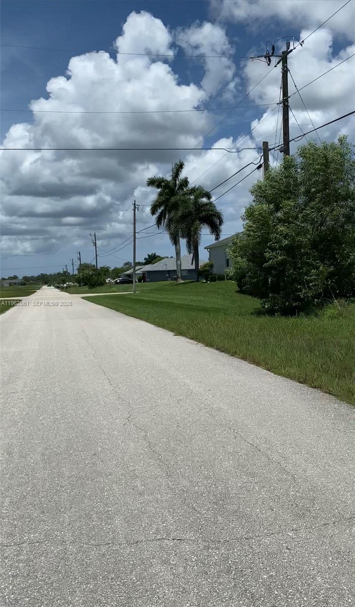 A paved road leads toward a residential area with palm trees and utility poles — 2 NW 13TH PL, Cape Coral FL 33993, CAPE CORAL, FL