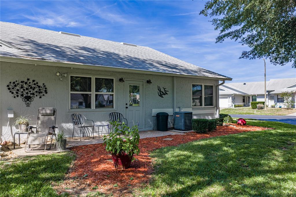 The exterior of a single-story house features a patio, lawn, and red mulch landscaping — 6380 EGRET DRIVE UNIT 6, LAKELAND, FL