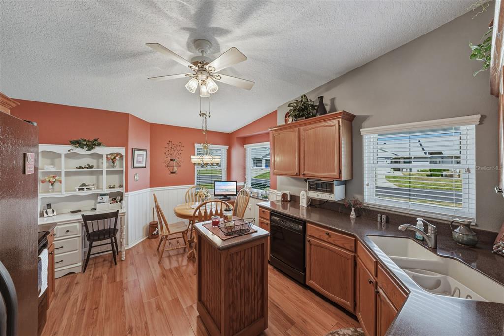 A kitchen with wood cabinets, a small island, and a dining area with orange walls — 6380 EGRET DRIVE UNIT 6, LAKELAND, FL