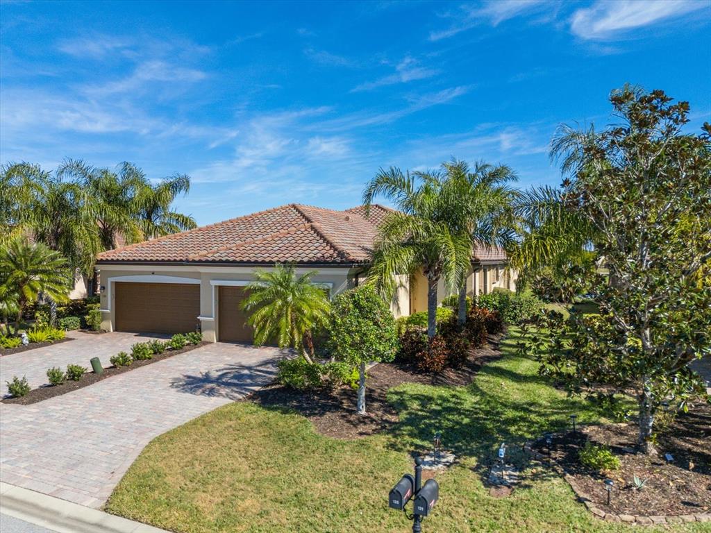 A single-story house with a tile roof, two-car garage, and palm trees in the yard — 131 BABBLING BROOK RUN, BRADENTON, FL