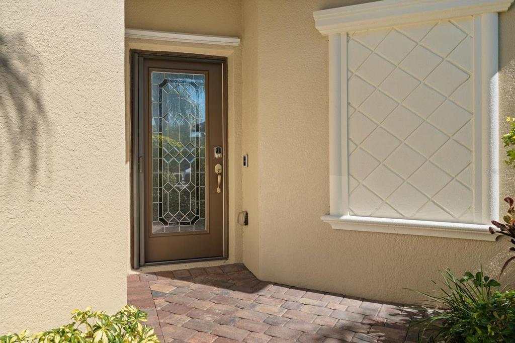 A front entryway features a brown glass-paneled door and a decorative window with lattice trim — 131 BABBLING BROOK RUN, BRADENTON, FL
