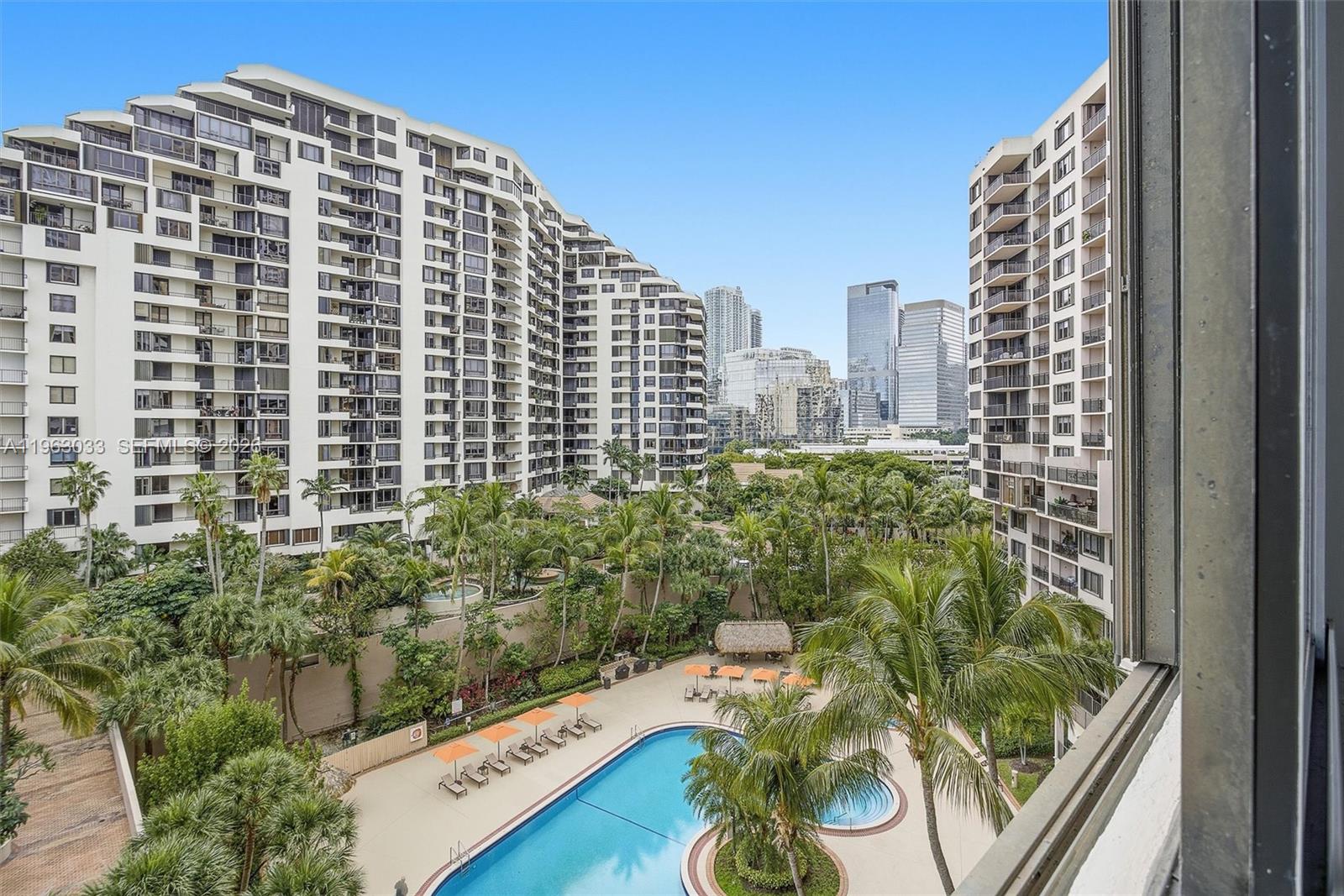 An elevated view of a swimming pool surrounded by palm trees and high-rise apartment buildings — 540 Brickell Key Dr # 823, Miami FL 33131, MIAMI, FL