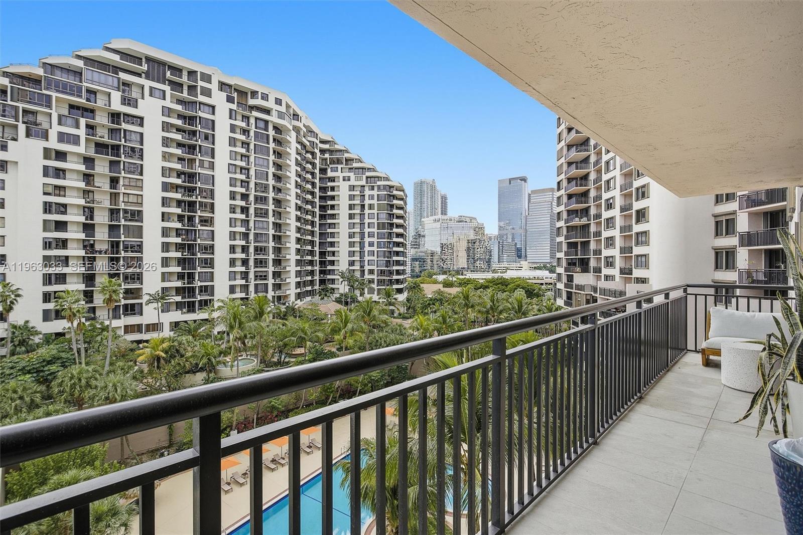 A balcony with a metal railing overlooks a swimming pool and surrounding high-rise apartment buildings — 540 Brickell Key Dr # 823, Miami FL 33131, MIAMI, FL