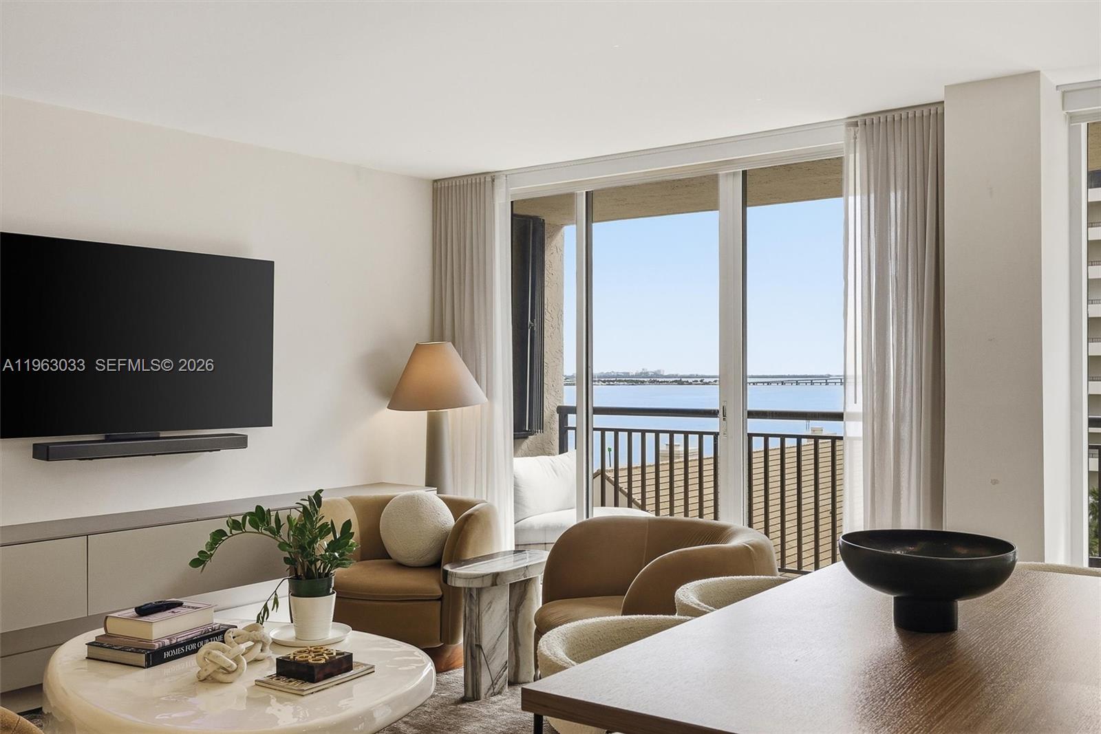 A living room features two tan armchairs, a marble coffee table, and a balcony view — 540 Brickell Key Dr # 823, Miami FL 33131, MIAMI, FL