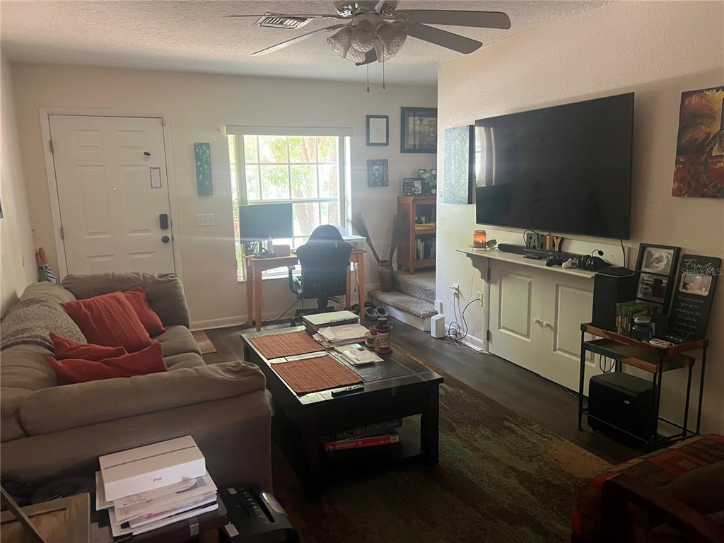 A living room features a large television, a sofa, a coffee table, and a desk — 1120 S MARY STREET, EUSTIS, FL