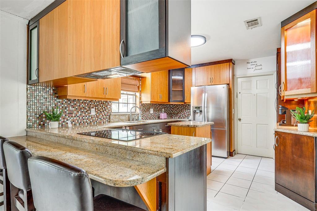 A kitchen features wood cabinets, granite countertops, a tiled backsplash, and stainless steel appliances — 920 LAKEVIEW DRIVE, WIMAUMA, FL