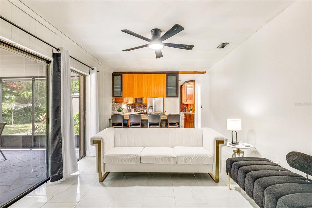 A living room with a white sofa, dark bench, and an open kitchen with bar seating — 920 LAKEVIEW DRIVE, WIMAUMA, FL
