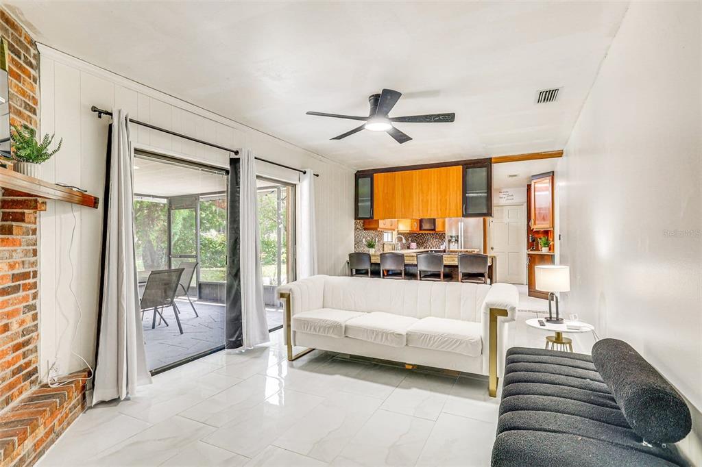 A living room with white tile floors, a white sofa, and an open kitchen area — 920 LAKEVIEW DRIVE, WIMAUMA, FL