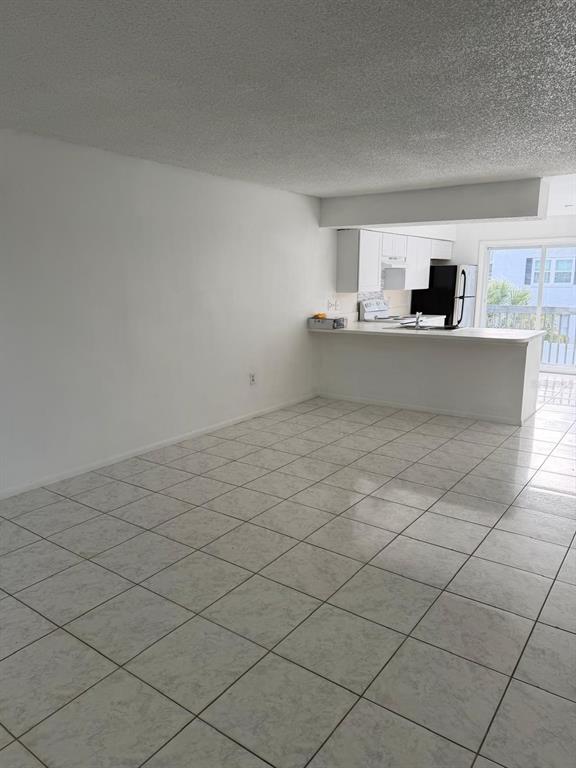An open-concept living area with white tile floors leads to a kitchen with white cabinets — 1854 CARALEE BOULEVARD UNIT 3, ORLANDO, FL