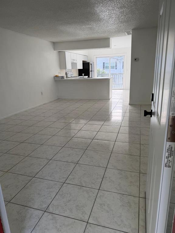 An open-concept living area features white tile flooring, a kitchen with white cabinets, and a balcony — 1854 CARALEE BOULEVARD UNIT 3, ORLANDO, FL