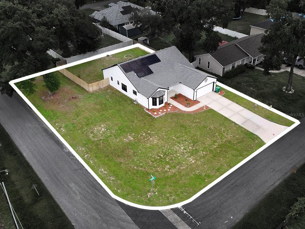 An aerial view shows a corner lot with a single-story house featuring solar panels — 370 CARRIAGE LANE, LADY LAKE, FL