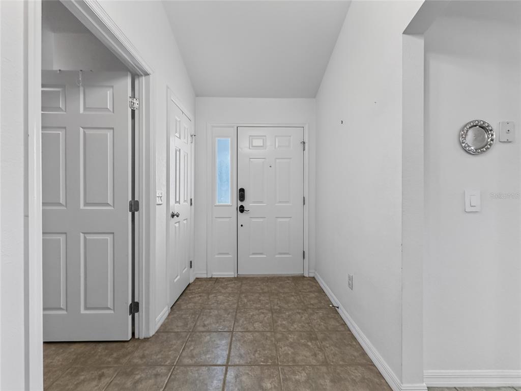 An entryway features white walls, a tiled floor, and a white front door with sidelight — 370 CARRIAGE LANE, LADY LAKE, FL