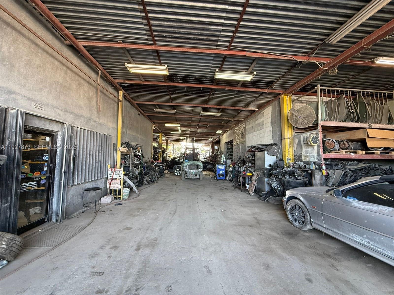 A large, open-air industrial warehouse space features a concrete floor, metal roof, and automotive parts — 12755 Cairo Ln, Opa-Locka FL 33054, OPA-LOCKA, FL