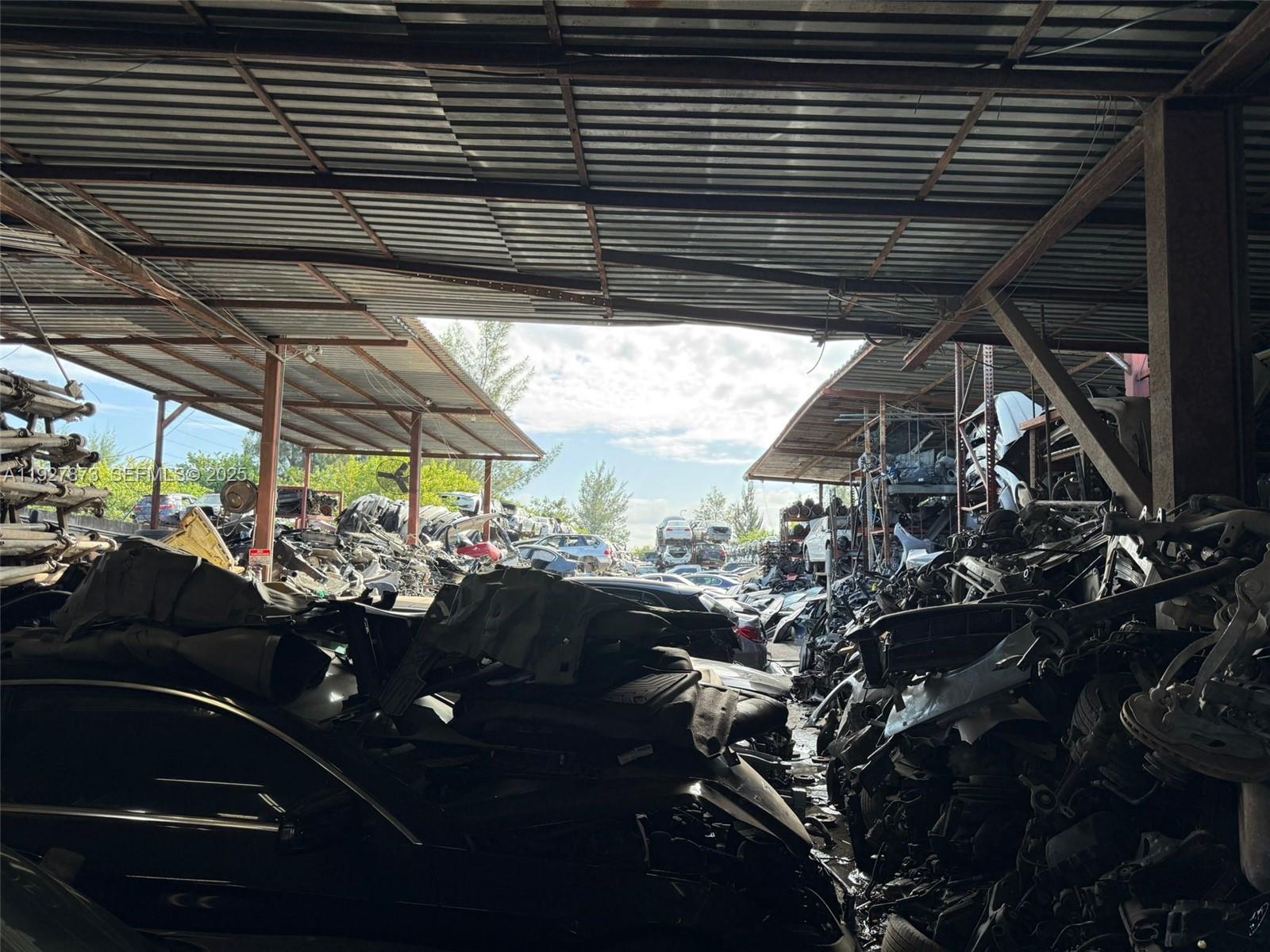 An outdoor salvage yard features rows of stacked car parts under metal roof structures — 12755 Cairo Ln, Opa-Locka FL 33054, OPA-LOCKA, FL