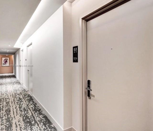 A hallway with patterned carpeting leads to a white door labeled 1206 — 4010 S Ocean Dr # R1206, Hollywood FL 33019, HOLLYWOOD, FL