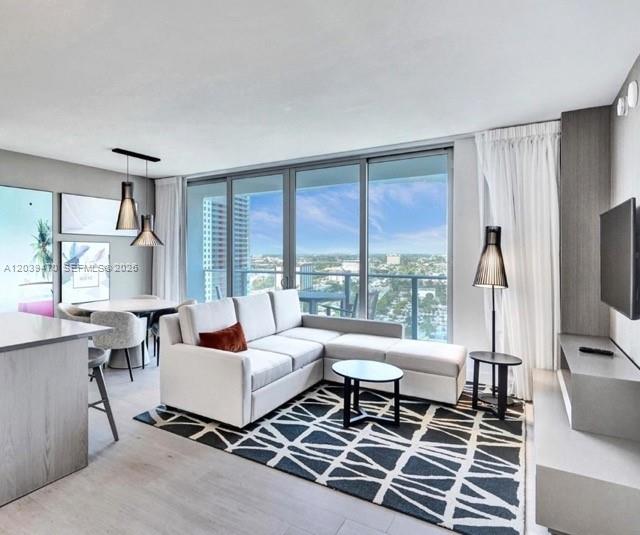 A modern living room features a white sectional sofa, a geometric rug, and floor-to-ceiling windows — 4010 S Ocean Dr # R1206, Hollywood FL 33019, HOLLYWOOD, FL