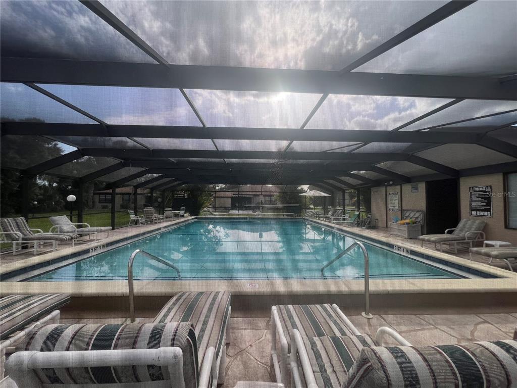 A screened-in swimming pool area features lounge chairs on a concrete deck — 4022 BEAVER LN NE UNIT 800 C, PORT CHARLOTTE, FL