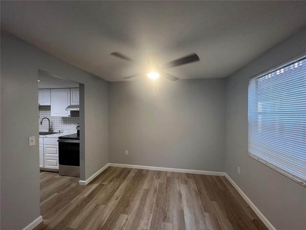 A dining area with wood-look flooring and a ceiling fan opens into a white kitchen — 4022 BEAVER LN NE UNIT 800 C, PORT CHARLOTTE, FL