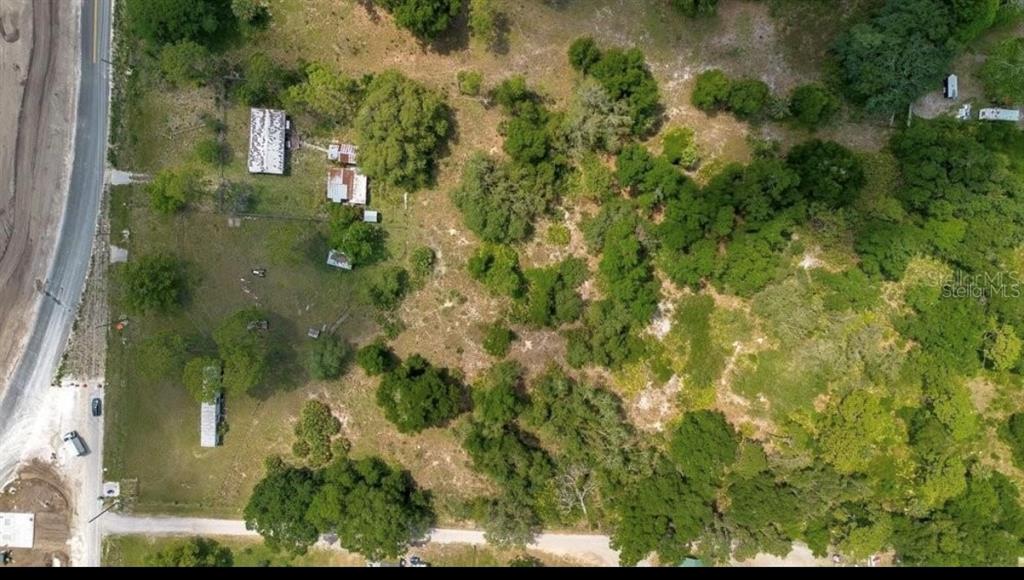 An aerial view shows a rural property with several small buildings, trees, and dirt paths — 1938 N LAKEWOOD AVENUE, OCOEE, FL