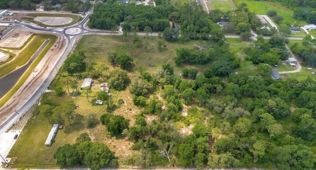 An aerial view shows a large, partially wooded plot of land with several small structures — 1938 N LAKEWOOD AVENUE, OCOEE, FL
