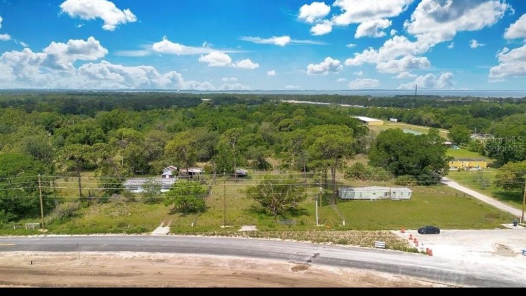 An aerial view shows a rural lot with two small structures, trees, and a paved road — 1938 N LAKEWOOD AVENUE, OCOEE, FL