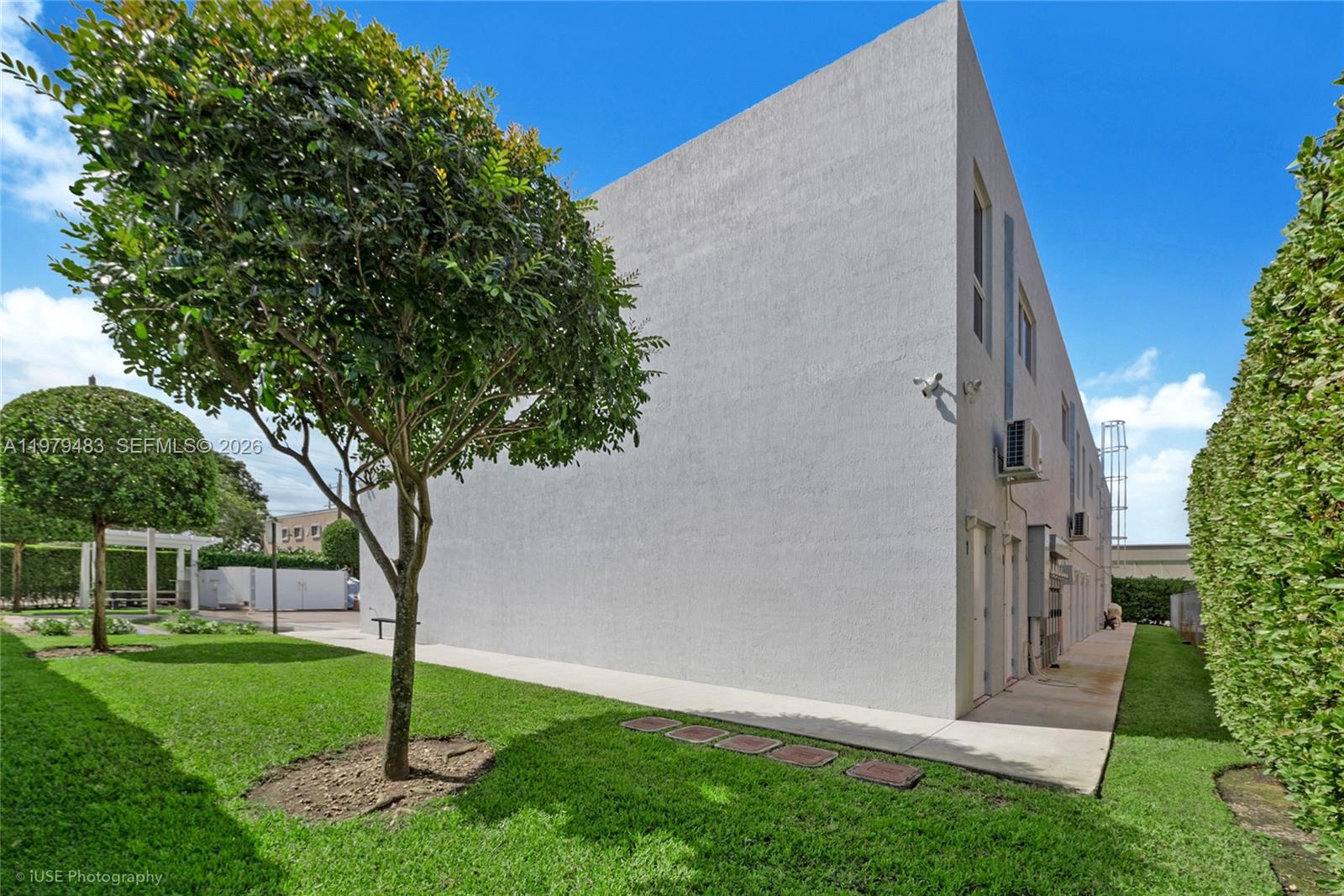 A large, plain white exterior wall of a building stands next to a green lawn — 13040 SW 123rd Ave, Miami FL 33186, MIAMI, FL