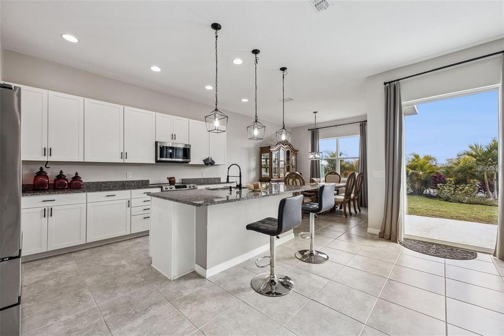 A kitchen with white cabinets, granite countertops, a center island, and a sliding glass door — 2091 BRILLANTE DRIVE, ST CLOUD, FL