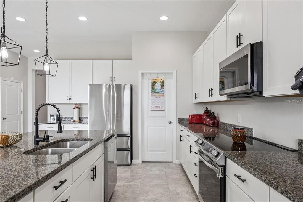 A kitchen features white cabinets, granite countertops, stainless steel appliances, and a central island — 2091 BRILLANTE DRIVE, ST CLOUD, FL